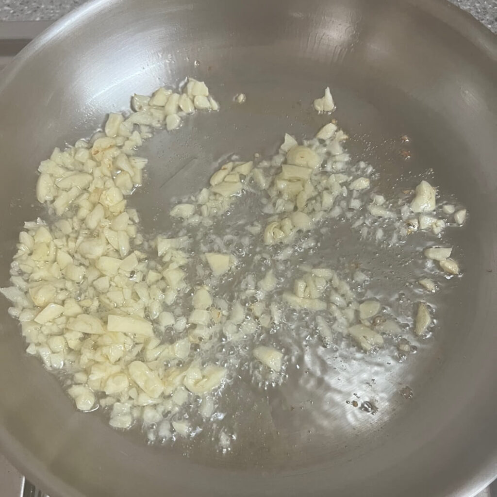 다진 마늘을 프라이팬에서 볶으며 마늘 기름을 내는 과정. 고기 시어링 전 풍미를 더하기 위한 작업.