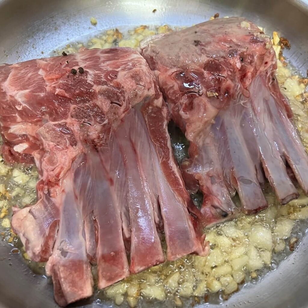 프라이팬에서 양갈비를 마늘 기름에 시어링하여 마이야르 반응을 일으키는 모습.