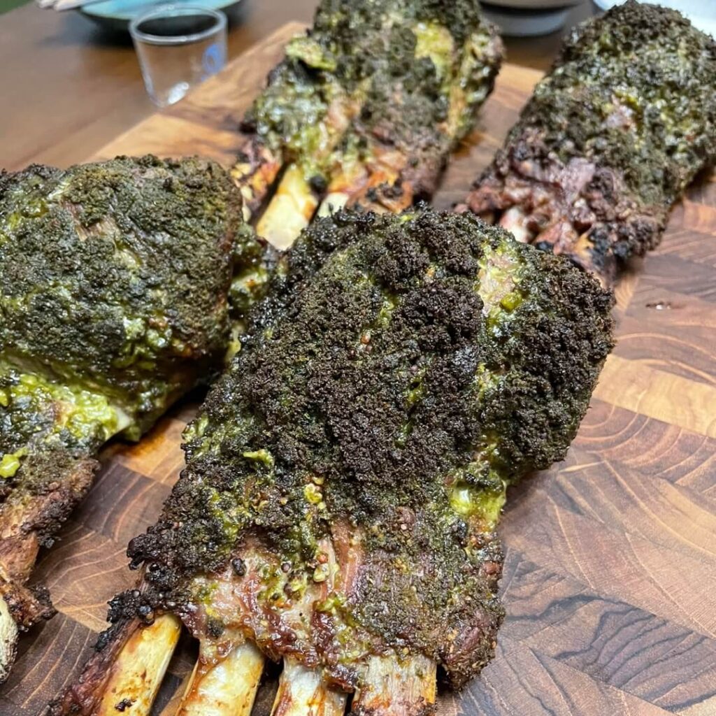 오븐에서 완성된 허브 크러스트 양갈비를 도마 위에 올려놓은 모습. 겉면은 바삭하고 내부는 촉촉하게 구워졌습니다.