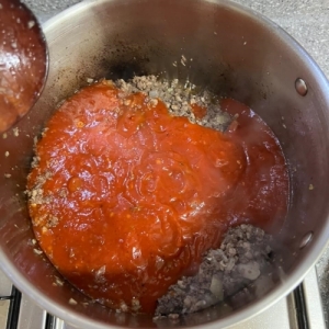 볶아진 고기에 토마토 소스를 추가하는 모습