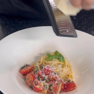 パルミジャーノ・レッジャーノチーズをパスタの上にすりおろした姿