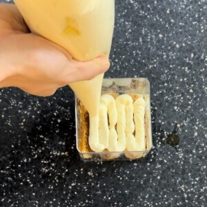 絞り袋でティラミスクリームをクッキーの上に絞り出すプロセス