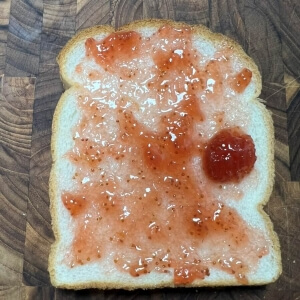 식빵 한 면에 딸기잼을 얇게 발라 준비한 모습.