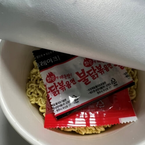 Buldak fried noodle cup noodle inside, with sauce and noodles ready to go