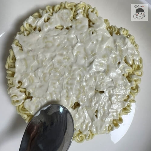 ラーメンの麺にマヨネーズを広く塗る様子