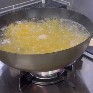 沸騰したお湯にパスタを入れて調理する様子