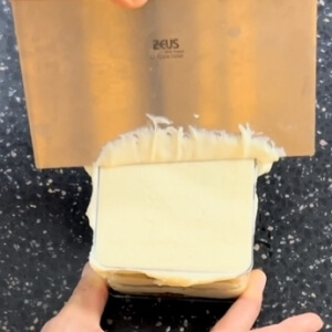 スクレーパーでティラミスクリームの表面をきれいに整頓する様子