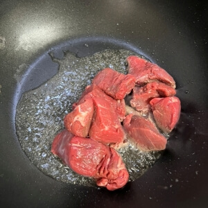 소고기 팬에 볶기 시작 이미지: 올리브오일을 두른 팬에 찹스테이크용 소고기를 볶기 시작한 모습.