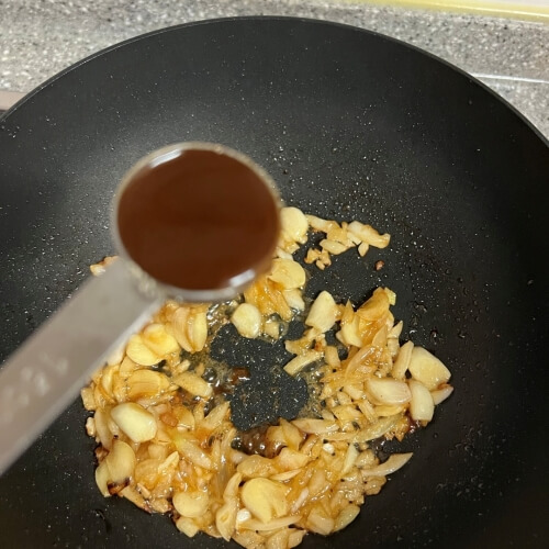 Adding a spoonful of A1 steak sauce to the pan-fried ingredients.