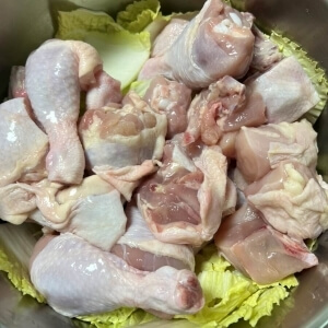 鍋に白菜と一緒に入れたトリミングされた鶏肉を入れる