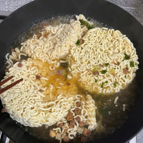 Spaghetti and raccoon noodles simmering in a pot.