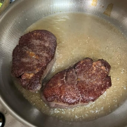센 불에서 시어링(겉면 익히기) 중인 스테이크 두 덩이
