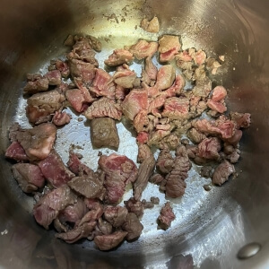 フライパンにごま油を熱し、牛肉を中火で炒める工程。
