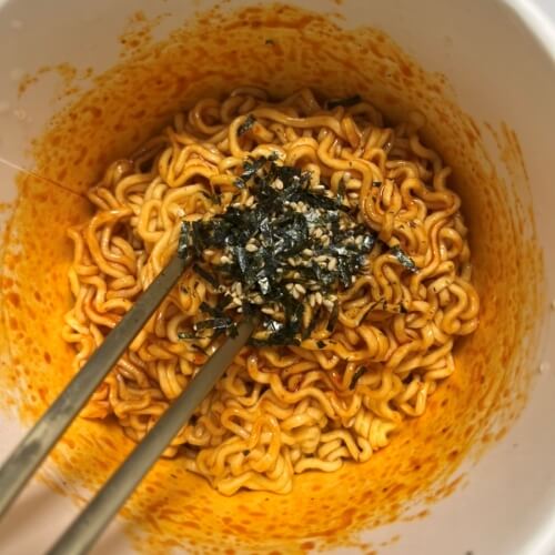 Bulgogi noodles topped with liquid sauce and fuchsia flakes