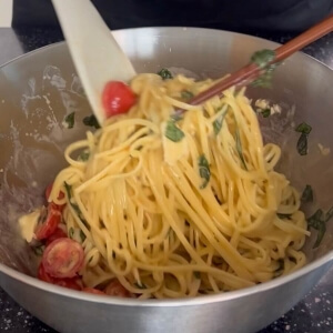 調理されたパスタを他の材料と一緒にボウルに入れる様子