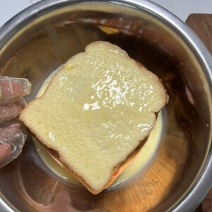 샌드위치 한 면에 계란물을 고르게 묻히는 모습.