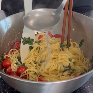 パスタの麺をボウルに注ぎ、材料を混ぜるシーン