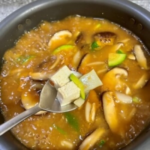 味噌汁の肝を確認するために、豆腐とズッキーニをすくうシーン。