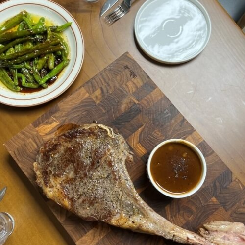 A table with a tomahawk steak and A1 steak sauce prepared next to it.