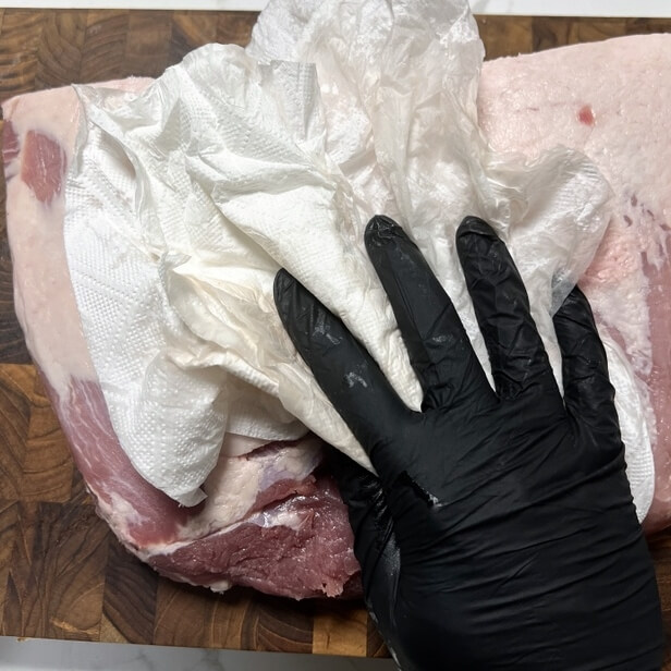 豚バラ肉を切る前にキッチンタオルで血を拭き取る様子。