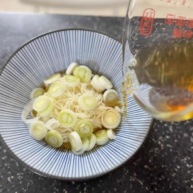 Adding the tzu yu dilution to the bowl with the somen noodles.