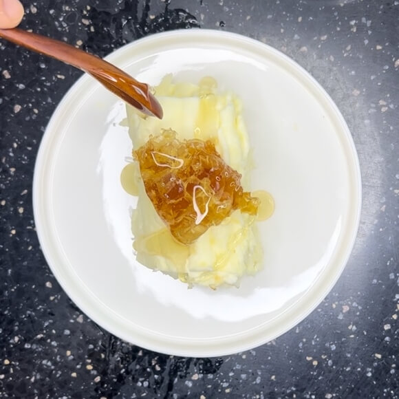 A honeycomb and honey drizzled over a caimak.