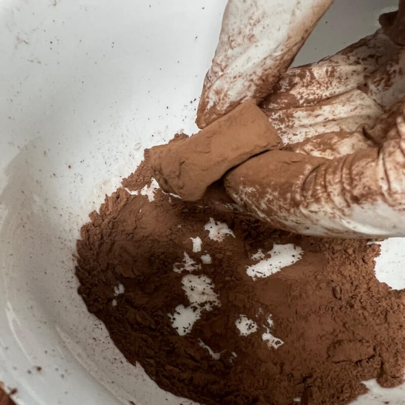 Dipping a cut section of chocolate in cocoa powder