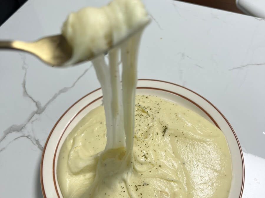 Aligot Potato Pomme Aligotのレシピを完成させ、お皿に盛り付け、フォークで伸ばしている様子。