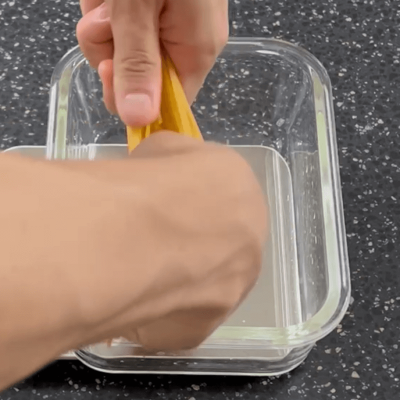 Breaking the pasta in half to fit the container.