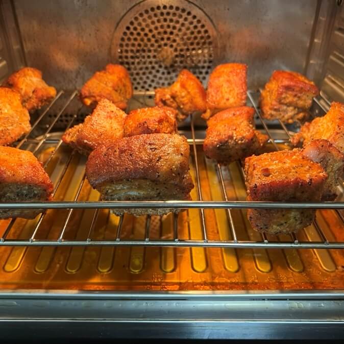 1次下処理が完了した豚バラ肉の様子と、その下に出てきた油がたっぷり入っている様子。