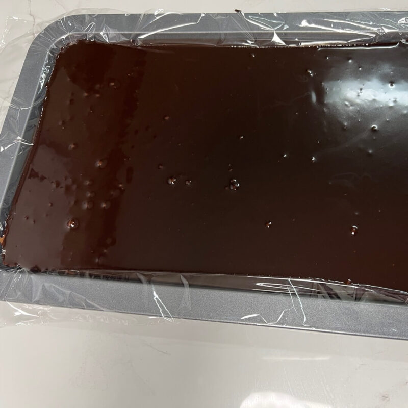 Melted chocolate poured into a tray lined with cling film