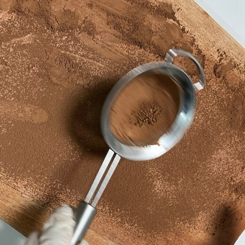 Sprinkling cocoa powder on a cutting board