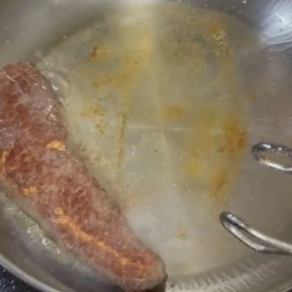 フライパンでステーキを焼く様子