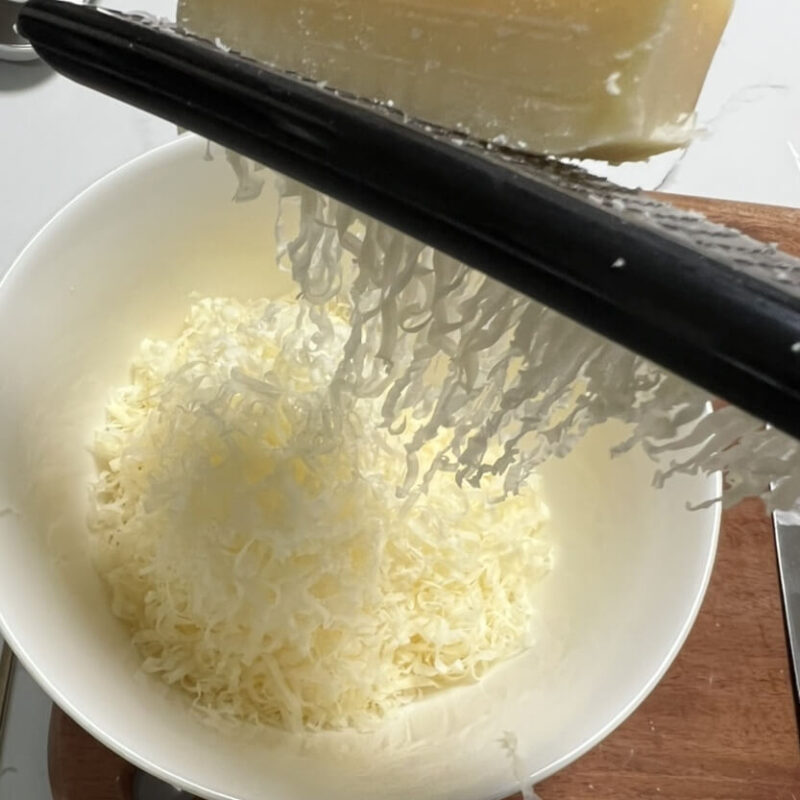 グリュイエールチーズをチーズおろし金ですりおろす様子
