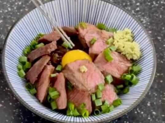 ステーキ丼のレシピを完成させ、ステーキの上にわさびを乗せている様子。