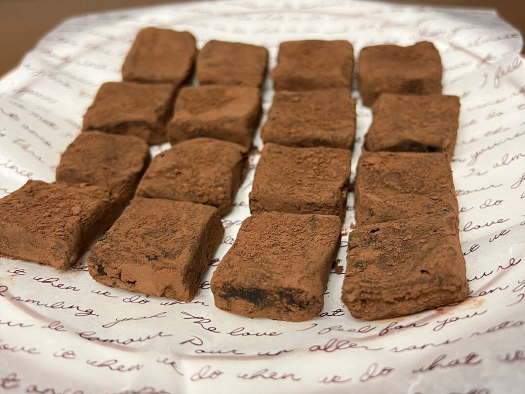 The finished pavé chocolate recipe, with 16 pieces of pavé chocolate on parchment paper.