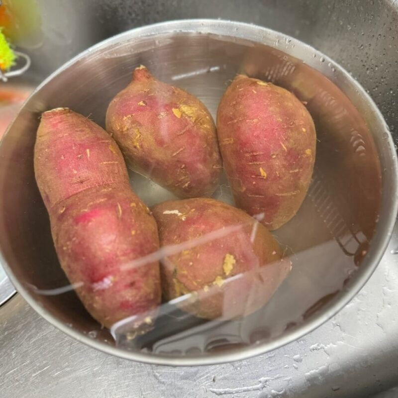 Soaking sweet potatoes in water to clean them.