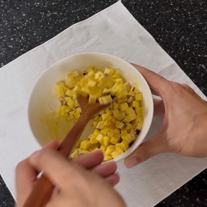Mixing the diced sweet potato, egg wash, and cornstarch until well combined