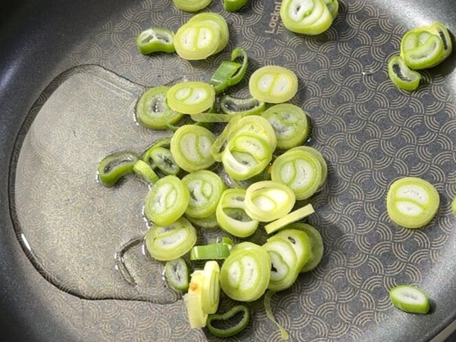 Cooking oil and scallions in a pan off the heat.