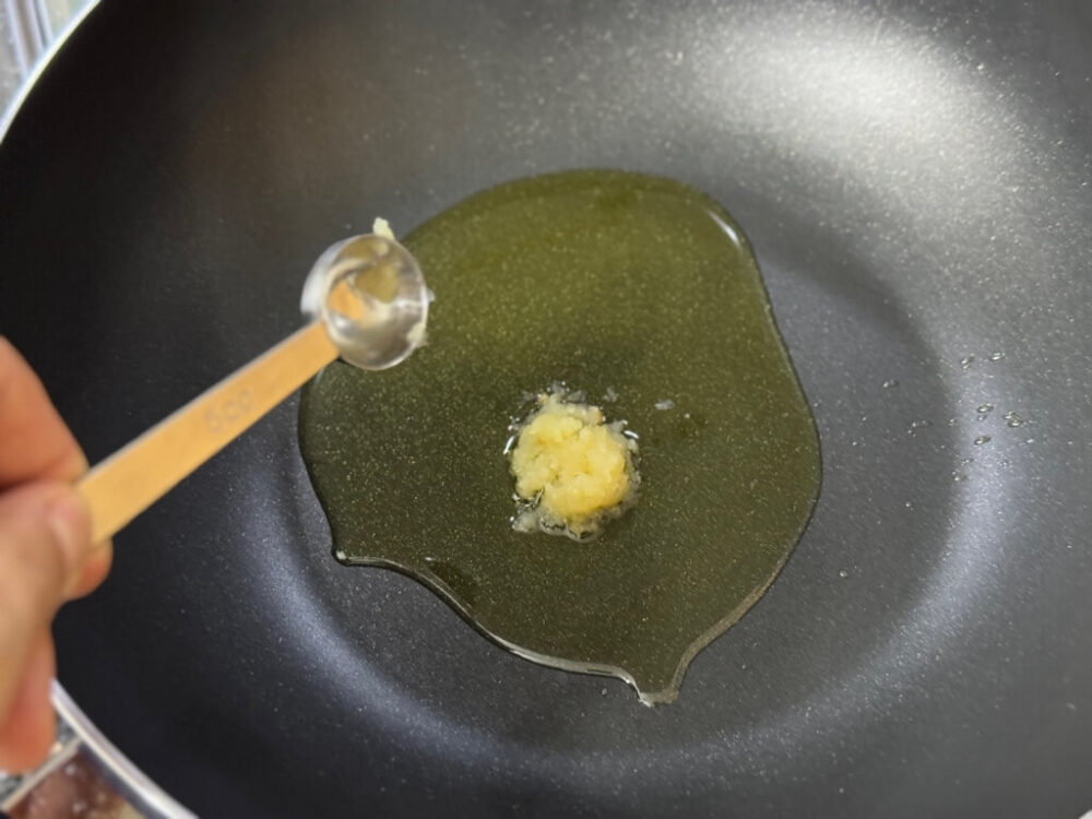 フライパンにみじん切りにんにくを入れる様子 