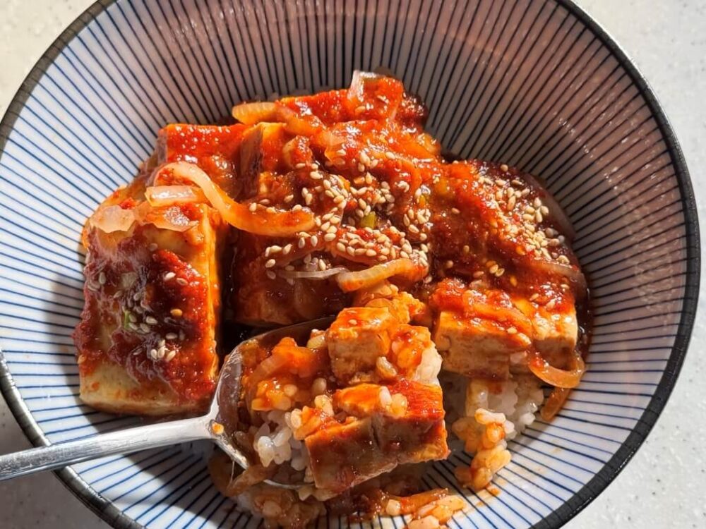 辛味豆腐丼のレシピを完成させ、スプーンで一口食べてみた様子