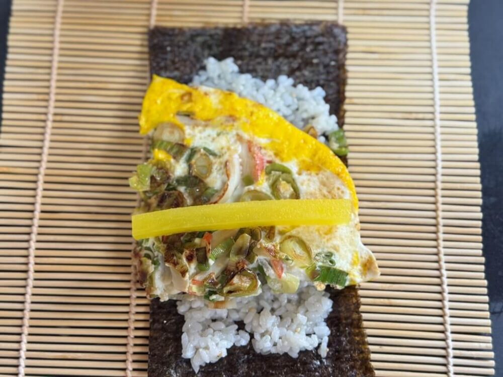 Un bol grande de arroz, coronado con una rodaja de huevo cebolleta y media tira de rábano daikon encurtido