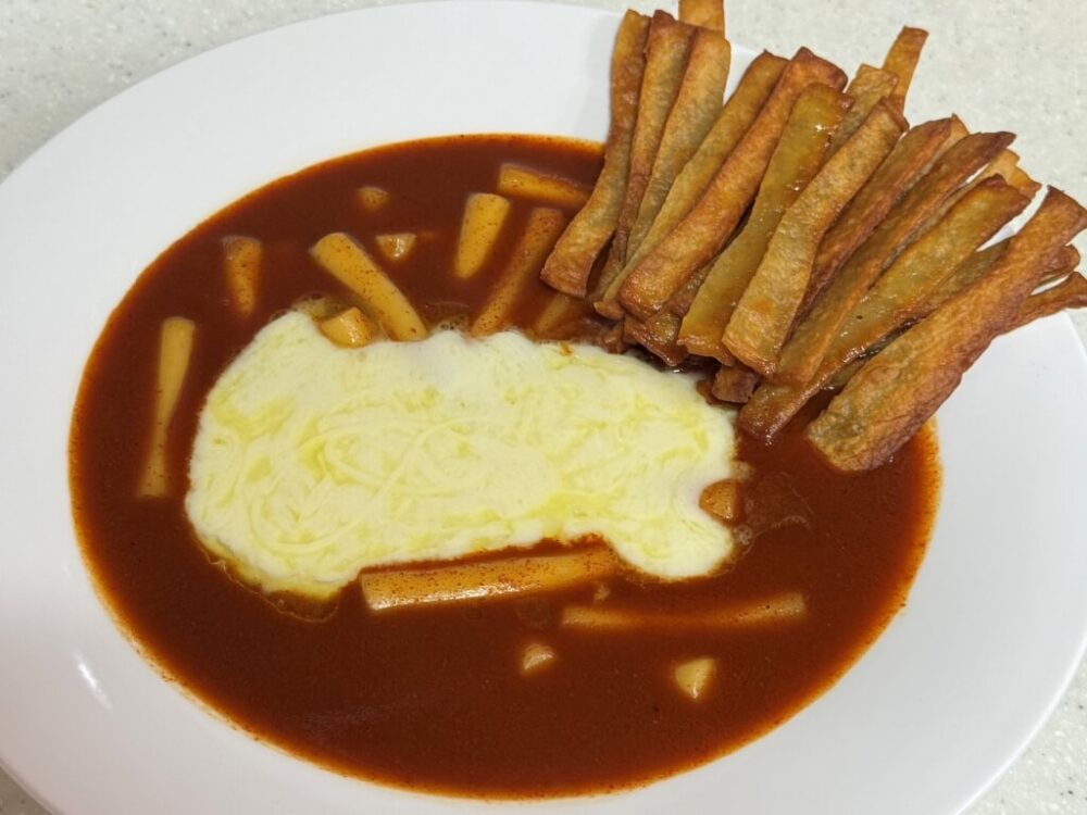La receta súper fácil de Sindeon Tteokbokki está lista, cubierta con queso y aderezos de pastel de pescado frito.