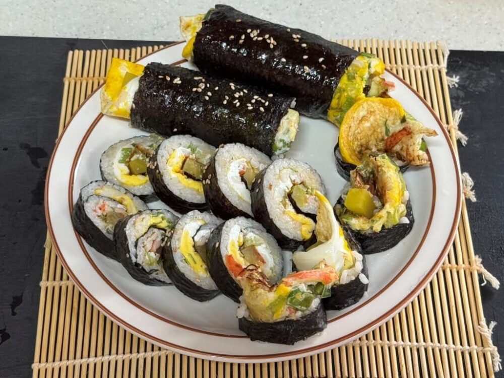 Esta receta de kimbap súper sencilla está completa, con dos filas de kimbap entero y cortado en el plato.