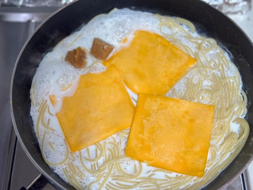 沸騰した牛乳にチェダーチーズとみじん切りにんにくを入れた様子。