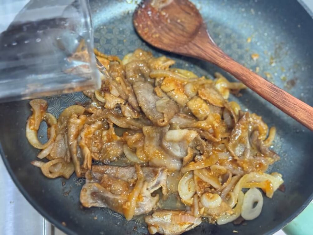 味付けされた豚バラ肉に水を入れて焼く様子