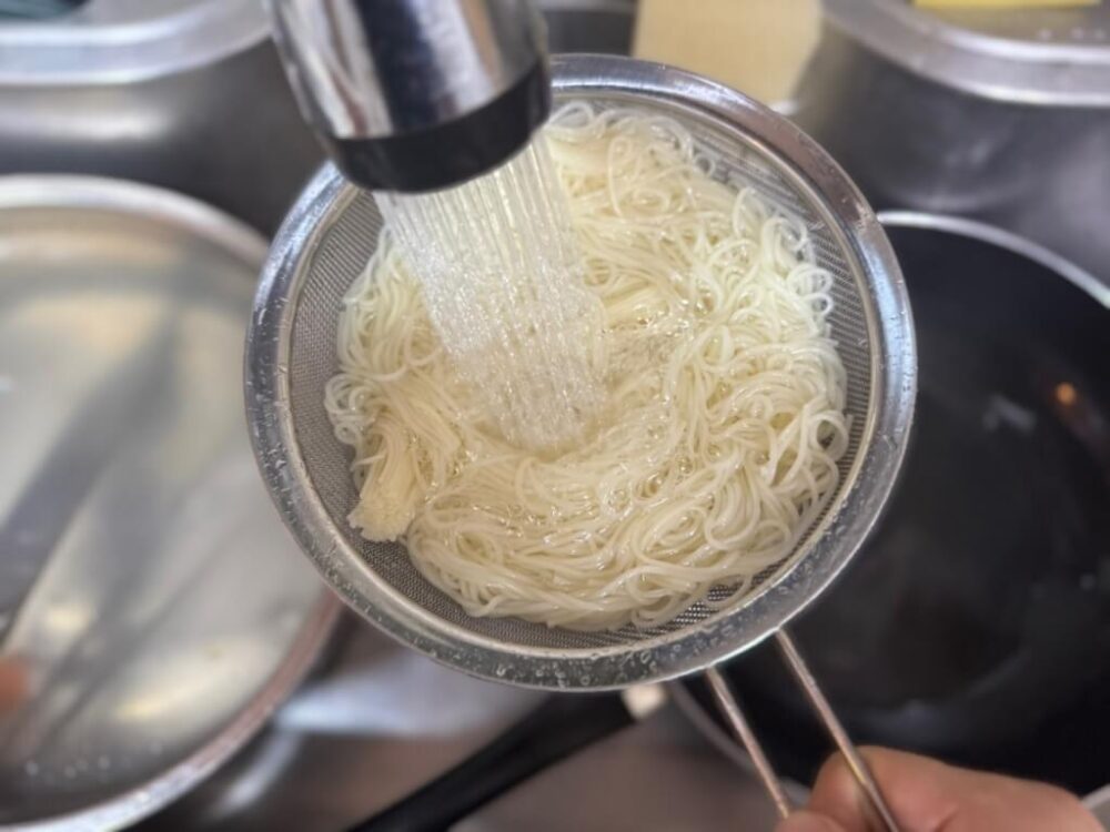 茹でた素麺を冷水で洗い流す工程写真