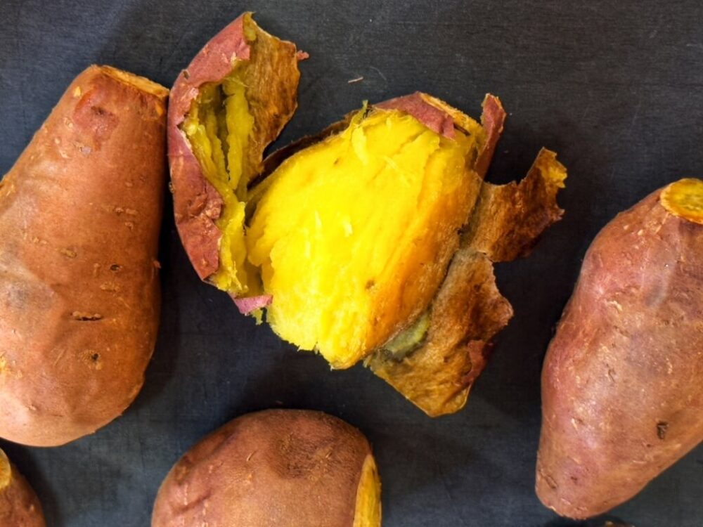 A baked sweet potato, cut open to reveal the yellow flesh.