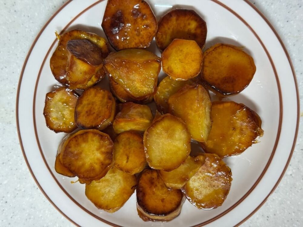 The finished Sweet Potato Pie Super Easy recipe, with a plate of sugar-coated fried sweet potatoes on the table.