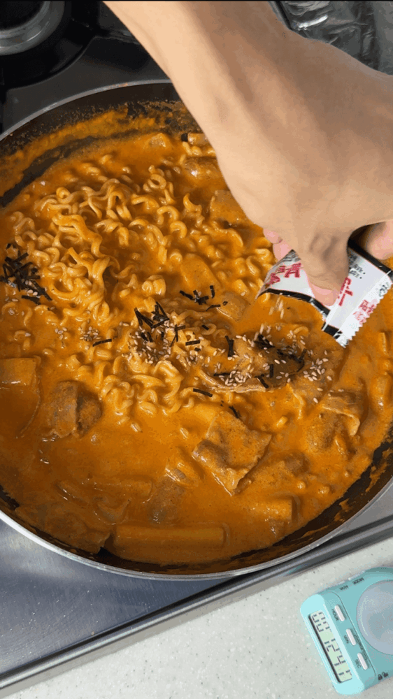 Completing the rosé buldak tteokbokki recipe with a sprinkling of seaweed flakes.